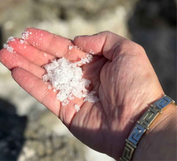 Hand holding freshly harvested Afrala sea salt crystals from Zakynthos, Greece; pure, sun-dried, mineral-rich salt symbolizing the finest natural essence of the sea. Zoi Maroudas Bambino’s Baby Food