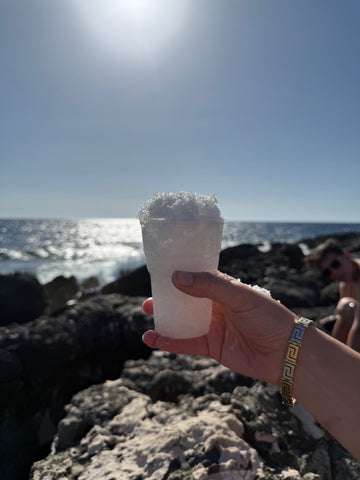 Cup filled with Afrala sea salt crystals, naturally sun-dried on the rocky coast of Zakynthos, Greece; showcasing the bright, delicate texture and exceptional quality of this artisanal sea salt. Bambino’s Baby Food Zoi Maroudas 